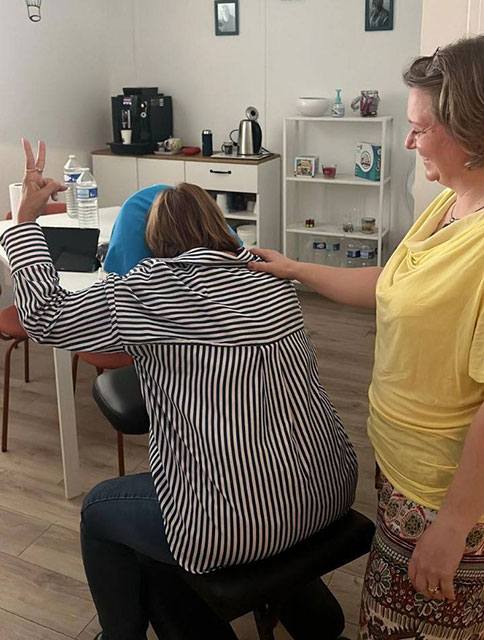 Praticienne bien-être à Plaisir effectuant un massage du dos assis méthode EAS® en entreprise à l’agence Petit-Fils, Yvelines